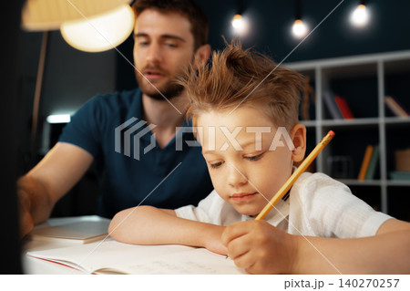 Dad and son doing school homework together 140270257
