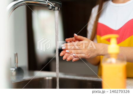 Close up of a woman washing her hands in a kitchen sink Close up of a woman washing her hands in a kitchen sink 140270326