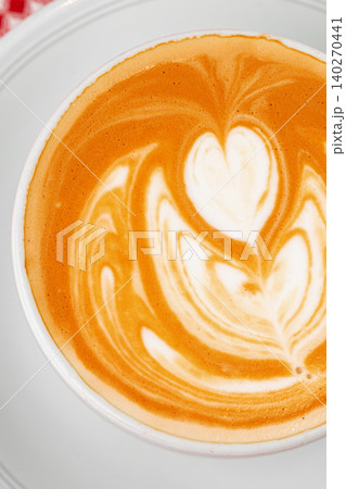 Latte art in a white cup with a heart design and warm brown tones 140270441
