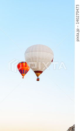 Hot air balloons rise into the clear sky over the countryside at dawn near a small town 140270473
