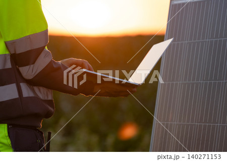 Engineer with laptop next to solar panel Engineer with laptop next to solar panel 140271153