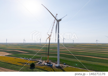 Wind turbine installation using a large construction crane. The assembly process of the turbine tower and rotor blades. Aerial view. 140271170