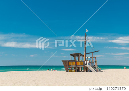 Wooden pirate ship playground on a sandy Mediterranean beach in Spain. Family recreation area near turquoise sea under blue summer sky Wooden pirate ship playground on a sandy Mediterranean beach in Spain. Family recreation area near turquoise sea under blue summer sky 140271570