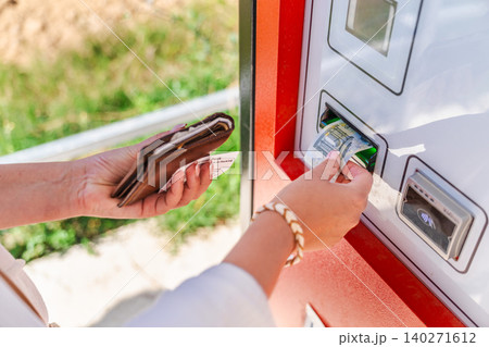 Woman paying cash at automated parking payment machine, inserting euro banknote while holding parking ticket and wallet at self service terminal Woman paying cash at automated parking payment machine, inserting euro banknote while holding parking ticket and wallet at self service terminal 140271612