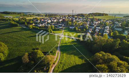 Aerial view of small town in western Germany surrounded by green fields and countryside landscape during warm sunset light Aerial view of small town in western Germany surrounded by green fields and countryside landscape during warm sunset light 140271629