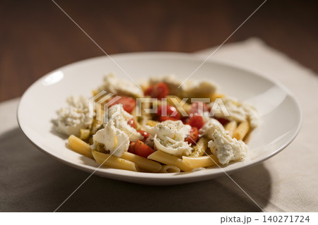 Penne pasta with mozzarella, pesto and fresh cherry tomatoes 140271724