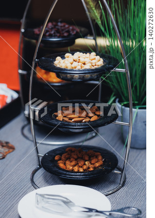 Metal tiered stand holds assorted nuts Metal tiered stand holds assorted nuts 140272630