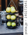 Fresh green apples sit neatly on tiered metal stand 140272641