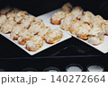 Almond-coated pastries gleam on white plates 140272664
