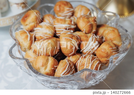 Golden choux pastries sit in a clear glass bowl Golden choux pastries sit in a clear glass bowl 140272666