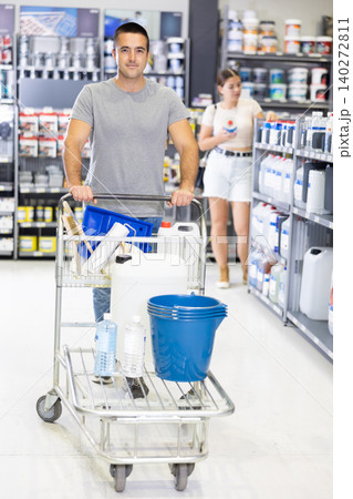 Man shoppers stand with trolley filled with goods for repair and coloring in supermarkets sales hall 140272811