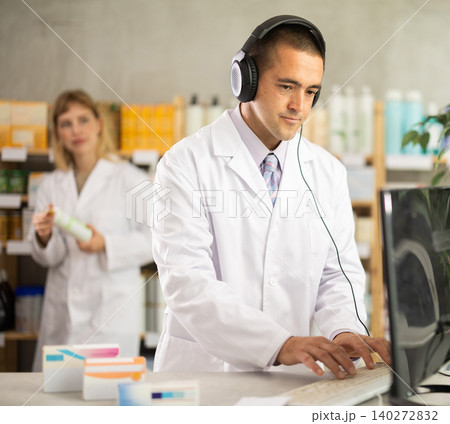 Male pharmacist working at computer in headphones Male pharmacist working at computer in headphones 140272832