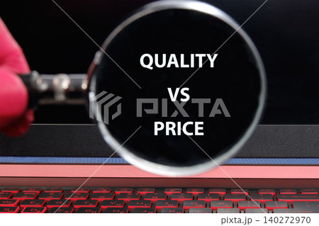 A hand holds a magnifying glass over a laptop screen displaying the phrase quality vs price, highlighting the focus on consumer decision-making in the digital age 140272970