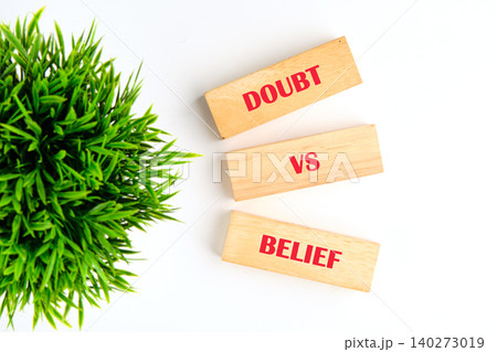 Two wooden blocks display the words doubt and belief against a clean background, accompanied by lush green foliage. This scene sparks reflection on personal convictions 140273019