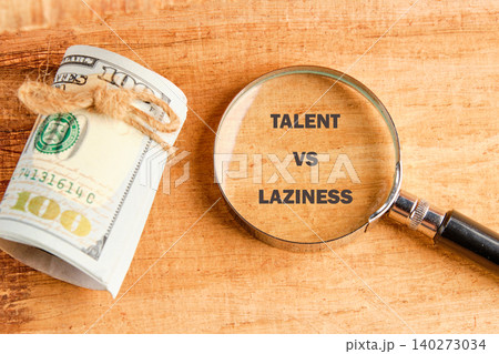 A magnifying glass highlights the words talent vs laziness next to a rolled hundred-dollar bill on a wooden table, symbolizing the contrast in personal growth and success A magnifying glass highlights the words talent vs laziness next to a rolled hundred-dollar bill on a wooden table, symbolizing the contrast in personal growth and success 140273034