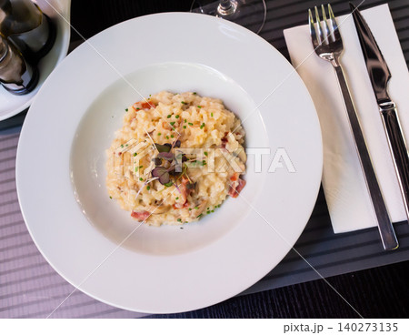 Creamy mushroom risotto with bacon garnished with greens Creamy mushroom risotto with bacon garnished with greens 140273135