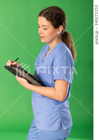 Young female medic in blue uniform checking data on tablet 140273155
