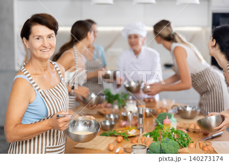 Lady while studying at culinary workshop, cooks appetizing sauce, marinade, dough in bowl 140273174