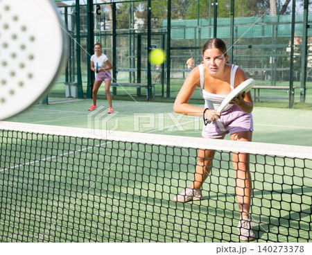 Young woman in shorts playing padel tennis on court Young woman in shorts playing padel tennis on court 140273378