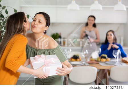 Girls hug and kiss on cheek when they meet, guest gives gift to birthday woman 140273384