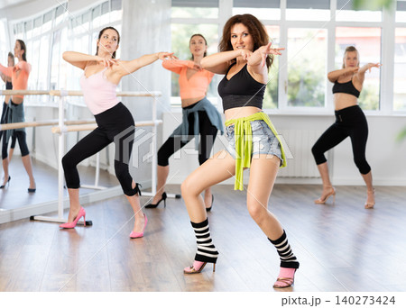 During lesson, woman learn to move and perform dance in heels with women companions During lesson, woman learn to move and perform dance in heels with women companions 140273424