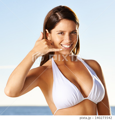 Portrait, call me and happy woman in swimsuit at beach for summer holiday, vacation or travel in nature. Face, phone gesture and person at sea for conversation, communication or sign by ocean water 140273542