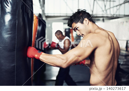 Fitness, punching bag and man with boxing gloves at a gym for training, resilience or performance. Sports, body and male boxer profile with punch practice for strength, energy for fighting exercise Fitness, punching bag and man with boxing gloves at a gym for training, resilience or performance. Sports, body and male boxer profile with punch practice for strength, energy for fighting exercise 140273617