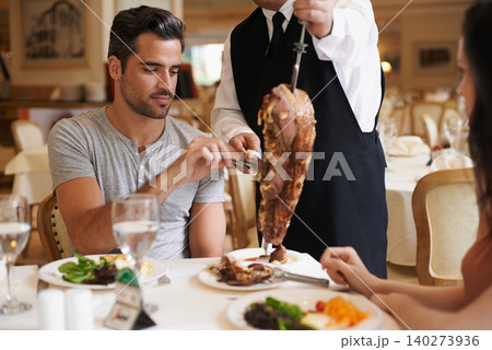 Couple, waiter and serving for lunch in restaurant with meat, happiness and fine dining for anniversary or honeymoon. Man, woman and employee with steak on skewer, healthy meal and table in London Couple, waiter and serving for lunch in restaurant with meat, happiness and fine dining for anniversary or honeymoon. Man, woman and employee with steak on skewer, healthy meal and table in London 140273936