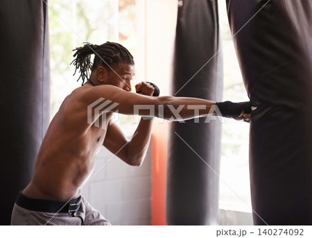 Fitness, punching bag and black man in gym for exercise, boxing challenge or competition training. Power, muscle and serious champion boxer at workout with confidence, fight and energy in sports club 140274092
