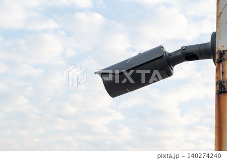 Modern surveillance camera mounted outdoors against cloudy sky providing security monitoring protection safety for public private areas 140274240
