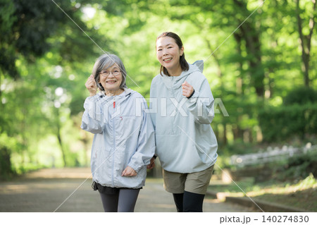 新緑背景でシニア女性と娘世代の女性が公園でランニングやウォーキングを楽しむ健康的なイメージ 新緑背景でシニア女性と娘世代の女性が公園でランニングやウォーキングを楽しむ健康的なイメージ 140274830