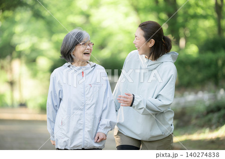新緑背景でシニア女性と娘世代の女性が公園でランニングやウォーキング(歩く,走る)のスポーツや運動 新緑背景でシニア女性と娘世代の女性が公園でランニングやウォーキング(歩く,走る)のスポーツや運動 140274838
