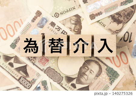 「為替介入」と書かれたブロックとたくさんの一万円札 140275326