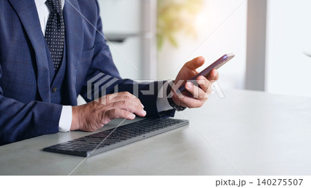 スマホとPCを使って作業する男性 140275507