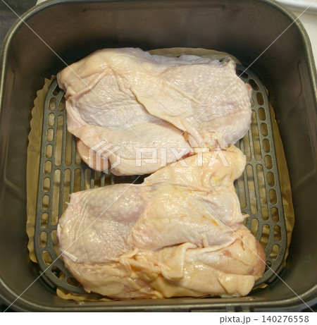 エアフライヤーにセットされた調理前の生の鶏もも肉、これから焼く前の準備風景 エアフライヤーにセットされた調理前の生の鶏もも肉、これから焼く前の準備風景 140276558