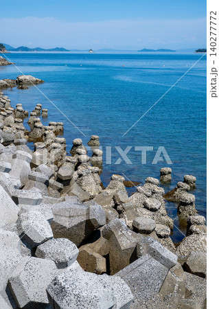 海岸に波消しブロック、遠くに小さい小島や島を望む波静かな海の風景 140277772