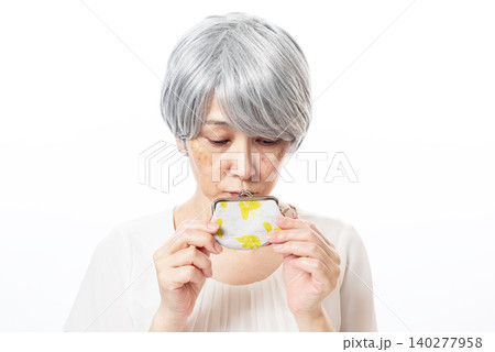 がま口を悲しそうに見つめる白髪のシニア女性 がま口を悲しそうに見つめる白髪のシニア女性 140277958
