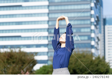 ビル街を背景にストレッチをしている女性 140278140