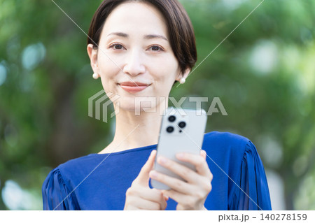 屋外でスマートフォンを操作している若い女性 140278159