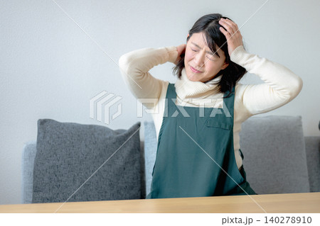 自宅で頭を押さえる女性 自宅で頭を押さえる女性 140278910