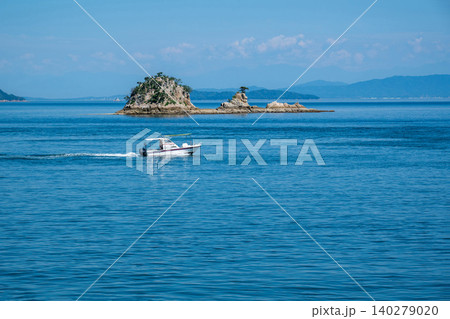 晴れた日の沖合の小さな島とゆっくり通り過ぎる小さな船 晴れた日の沖合の小さな島とゆっくり通り過ぎる小さな船 140279020