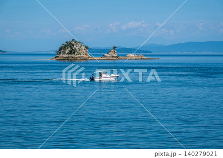 晴れた日の沖合の小さな島とゆっくり通り過ぎる小さな船 晴れた日の沖合の小さな島とゆっくり通り過ぎる小さな船 140279021