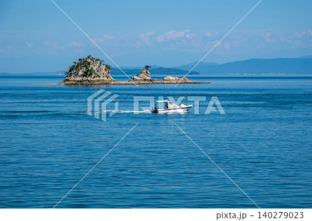 晴れた日の沖合の小さな島とゆっくり通り過ぎる小さな船 晴れた日の沖合の小さな島とゆっくり通り過ぎる小さな船 140279023