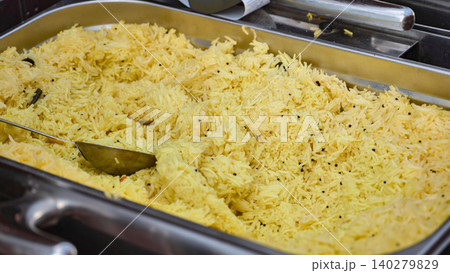 Chef serving indian saffron rice with metal spoon in buffet tray 140279829
