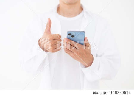 スマホを持ってサムズアップする白いシャツを着たミドル男性白バック スマホを持ってサムズアップする白いシャツを着たミドル男性白バック 140280691