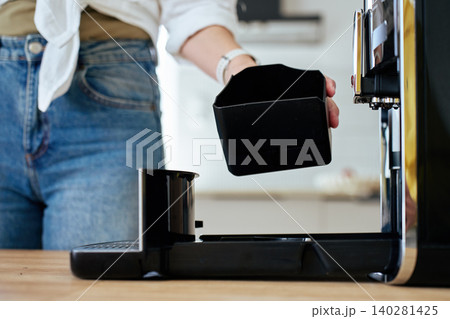 Person removing coffee machine container for cleaning Person removing coffee machine container for cleaning 140281425