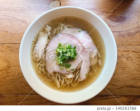 A steaming bowl of ramen with rich broth, tender noodles, sliced pork, boiled egg, nori, and fresh green onions. A comforting and flavorful Japanese classic. 140281566