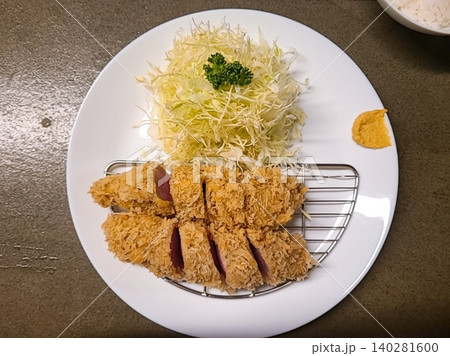 Crispy tonkatsu, a Japanese-style breaded and deep-fried pork cutlet, served with shredded cabbage and drizzled with savory sauce. A delightful balance of crunchy texture and juicy meat. 140281600