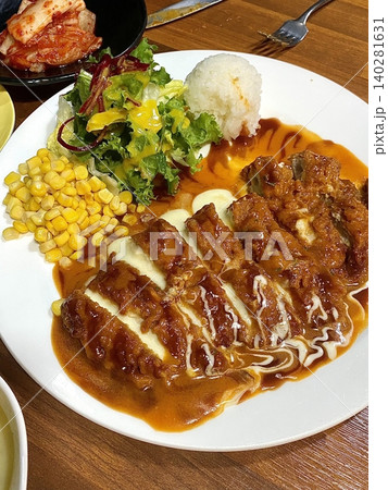 Crispy tonkatsu, a Japanese-style breaded and deep-fried pork cutlet, served with shredded cabbage and drizzled with savory sauce. A delightful balance of crunchy texture and juicy meat. Crispy tonkatsu, a Japanese-style breaded and deep-fried pork cutlet, served with shredded cabbage and drizzled with savory sauce. A delightful balance of crunchy texture and juicy meat. 140281631