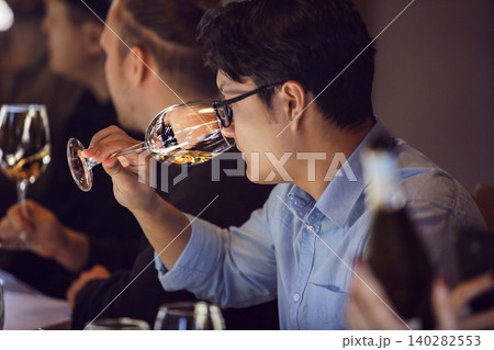 Asian Sommelier Evaluating White Wine by Olfactory Assessment at Professional Tasting Event Asian Sommelier Evaluating White Wine by Olfactory Assessment at Professional Tasting Event 140282553